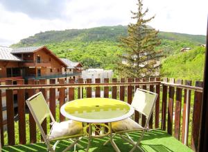 une table et des chaises sur un balcon avec un arbre dans l'établissement Coquet appartement Type 2 de 56 m² en centre ville, à Briançon