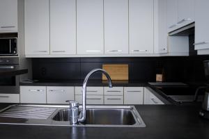 a kitchen with a sink and white cabinets at Maison Remy in Ypres