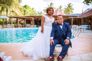 a bride and groom sitting next to a pool at Victory Hotel & Restaurant Tulear in Toliara +70 photos