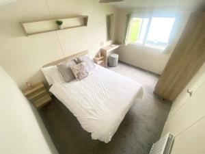 a bedroom with a white bed and a window at CW77 St Osyth Beach Holiday Park in Saint Osyth