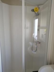 a bathroom with a shower and a toilet with a sign at CW77 St Osyth Beach Holiday Park in Saint Osyth