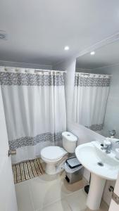 a white bathroom with a toilet and a sink at Hermoso y Tranquilo Departamento / Parquemar 3 in El Tabo