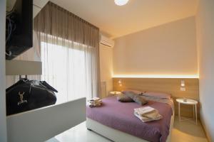een slaapkamer met een bed met paarse lakens en een raam bij Prime Blue Suite - Bilocale in Riccione