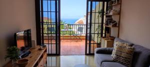 een woonkamer met een bank, een televisie en een balkon bij Sommer Sonnenhaus in Santa Cruz de Tenerife