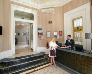 un hombre y una mujer parados en un mostrador en Lansbury Heritage Hotel en Londres