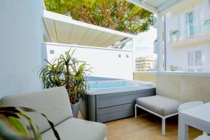 a balcony with a tub and a chair and plants at Prime Blue Suite - Appartamenti con jacuzzi privata in Riccione