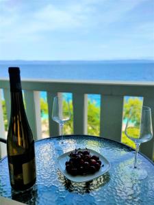 einen Tisch mit einer Flasche Wein und einem Teller Trauben in der Unterkunft Apartments Blueness in Prigradica