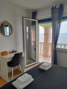 Schlafzimmer mit einem Bett, einem Schreibtisch und einem Fenster in der Unterkunft Apartments Blueness in Prigradica
