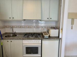a kitchen with white cabinets and a stove and a sink at SERVICE APART LAZARO TOPACIO 3 in Calpe