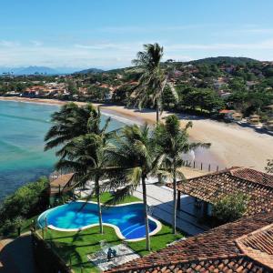 an aerial view of a beach with a swimming pool and palm trees at Bravacasa Geriba B&uacute;zios Luxury Inn in B&uacute;zios