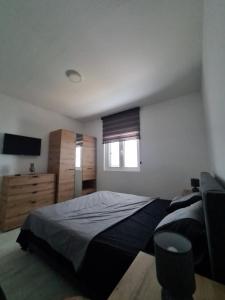 een slaapkamer met een bed, een dressoir en een raam bij Apartment Nikčević in Tivat