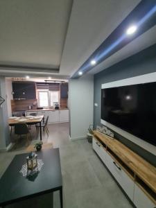 un soggiorno con grande TV e tavolo di Apartment Nikčević a Tivat