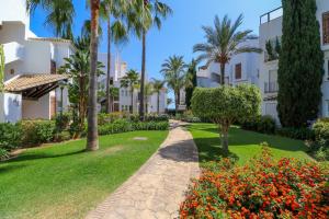 ścieżka przez ogród z palmami i kwiatami w obiekcie Family apartment with garden- Los Monteros Palm Beach w Marbelli