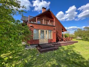 a house with a deck and chairs in the yard at Schneider in Pāvilosta