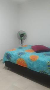 a bed with a colorful comforter and a fan at Apartamento completo medellin in Medellín