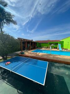 a pool with a tennis court in front of a house at Hostel Raizer in Campo Grande