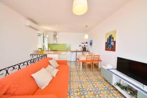 sala de estar con sofá naranja y cocina en A' casa 'e Carmeniello en Isquia