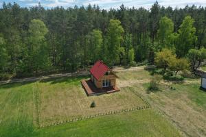a small house with a red roof in a field at Samosiejka - z widokiem na jezioro in Lidzbark +8 photos