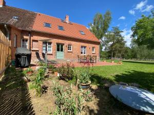 ein Haus mit einem Garten und einem Boot im Hof in der Unterkunft Forsthaus Zartwitzer Hütte in Rechlin