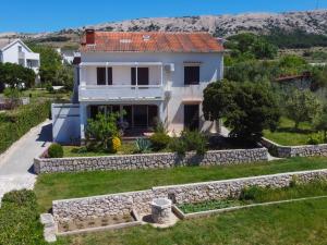 a house with a stone wall and a yard at Apartmani Nana Mija in Pag