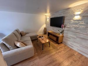 uma sala de estar com um sofá e uma televisão numa parede de pedra em • Bel appartement - centre historique de Poitiers em Poitiers