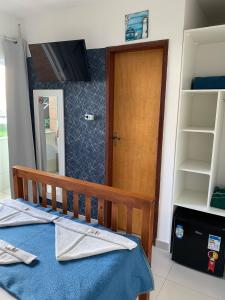 1 dormitorio con 1 cama y puerta de madera en Americano's Suítes, en Arraial do Cabo
