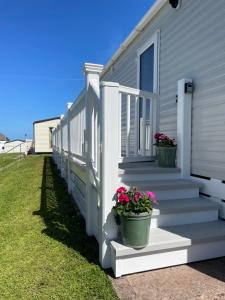 a white house with two potted plants on the stairs at Hoburne Devon Bay - Hot Tub 2 Bed Paignton in Paignton