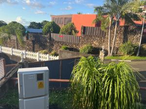 a parking meter sitting in the grass next to a fence at La maison du bonheur Papeete in Papeete