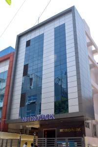 een gespiegeld gebouw met een metroparkbord erop bij Metro Park in Chennai