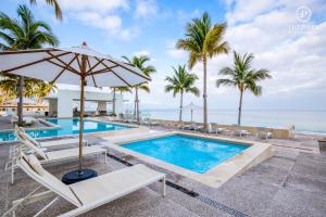 a pool with chairs and an umbrella next to the ocean at Harbor Puerto Vallarta 5009 in Puerto Vallarta