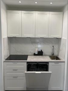 a white kitchen with white cabinets and a sink at MARICAMPO Monolocale con piscina e parcheggio in Marina di Campo