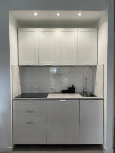 a white kitchen with white cabinets and a sink at MARICAMPO Monolocale con piscina e parcheggio in Marina di Campo