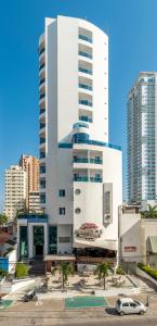 un grande edificio bianco con un'auto parcheggiata di fronte di Hotel Atlantic Lux a Cartagena de Indias