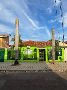 zielony budynek z dwoma kolumnami i bramą w obiekcie Hostel Raizer w mieście Campo Grande
