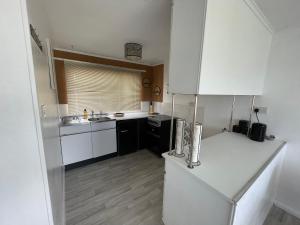 a kitchen with a white refrigerator and a sink at Romney Sands Holiday Apartment in New Romney