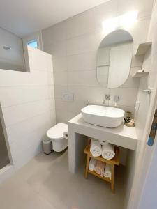 a white bathroom with a sink and a toilet at Kirki Rooms by the sea in Parikia