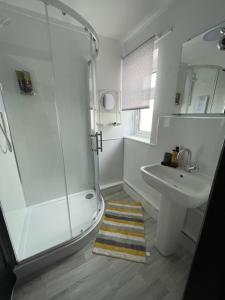 baño blanco con ducha y lavamanos en Romney Sands Holiday Apartment en New Romney