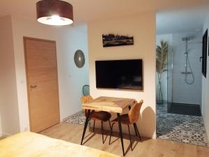 a dining room with a table and a tv at Le Domaine de Pivette in Avranches