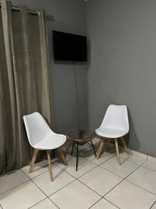 two white chairs and a table in a room at Tshukudu Guesthouse in Soweto
