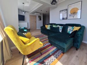 ein Wohnzimmer mit einer grünen Couch und gelben Stühlen in der Unterkunft Sailor Apartament Nadmorski 30 in Ustronie Morskie
