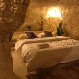 a group of three beds in a stone room at 7 Caves Hotel in Al Jāyah