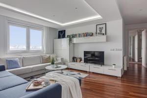 a living room with a couch and a tv at Riazor Ocean View Apartment in A Coruña