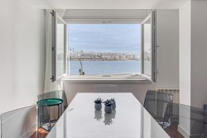 un comedor con una mesa blanca y una ventana en Riazor Ocean View Apartment, en A Coruña