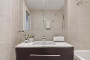 a white bathroom with a sink and a mirror at Riazor Ocean View Apartment in A Coruña