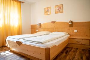 ein Holzbett in einem Schlafzimmer mit einem Kopfteil aus Holz in der Unterkunft Wiesgut in Völlan