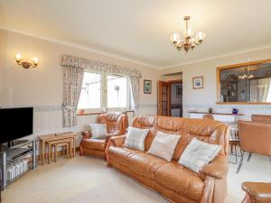 a living room with a leather couch and a television at Braehead Croft in Portessie
