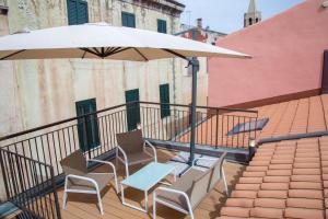 - un balcon avec 2 chaises et une table sous un parasol dans l'établissement Alguer Relais, à Alghero