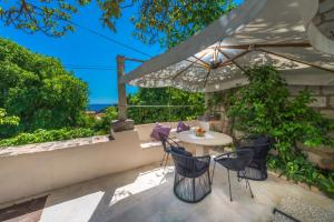 einen Tisch und Stühle auf einer Terrasse mit Sonnenschirm in der Unterkunft Villa Flores Garden in Dubrovnik
