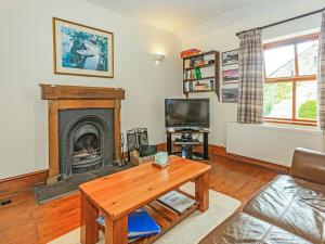 a living room with a fireplace and a tv at Carn Cottage in Long Preston