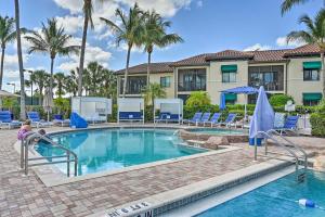 a pool at a resort with blue chairs and palm trees at Luxe Naples Bay Resort Condo Near Fifth Ave! in Naples